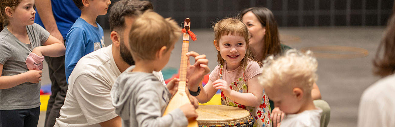Studentin coacht vier Kinder musikalisch mit Trommeln und Gesang