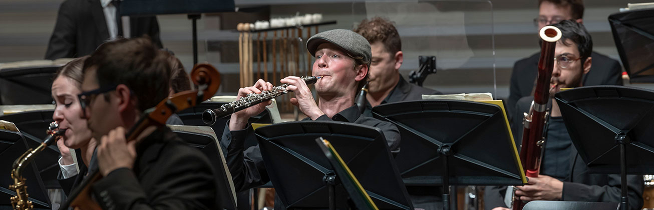 Ein Orchester spielt auf einer Bühne. Im Vordergrund sind Musiker mit Blasinstrumenten zu sehen, darunter eine Oboe, Saxophon und Fagott. Bild HSLU/Xenia Zezzi