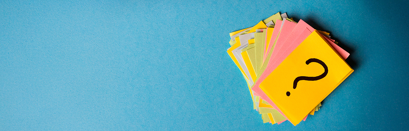 Ein Stapel bunter Karteikarten auf einem blauen Hintergrund, die oberste Karte ist gelb und zeigt ein schwarzes Fragezeichen.