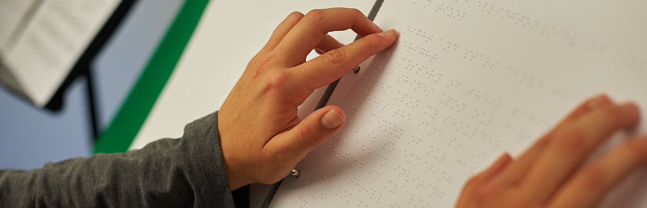 Zwei Hände lesen Noten in Braille-Schrift.