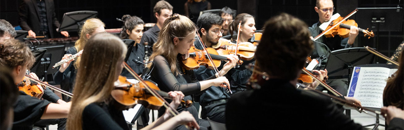 Das HSLU Streichorchester konzentriert mit spielenden Musiker:innen auf einer Konzertbühne. Bild HSLU/Xenia Zezzi