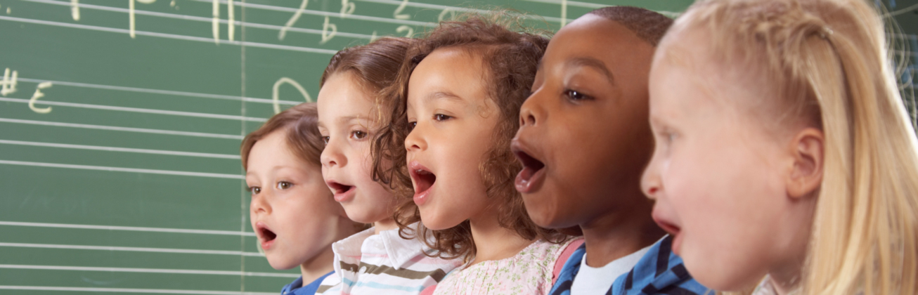 Fünf Kinder die zusammen singen vor einer grünen Wandtafel