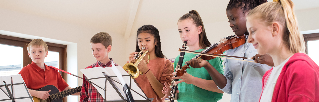 sechs Kinder die zusammen musizieren, spielen Geige, Trompete und Gitarre