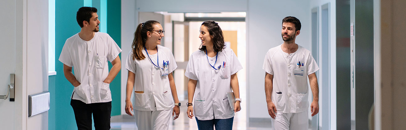  Junges Pflegeteam diskutiert während des Gehens in einem Spitalflur.