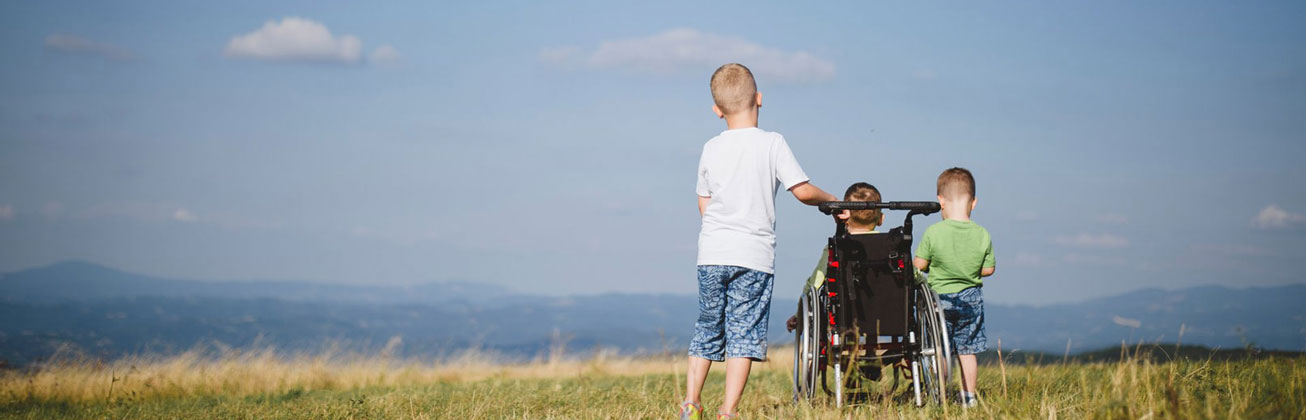 Drei Kinder von hinten, eines im Rollstuhl