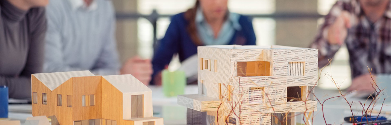 Im Vordergrund Architekturmodelle, hinten schemenhaft Menschen