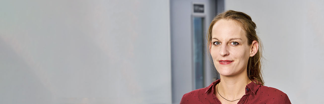 Eine Masterstudentin mit roter Bluse vor einem weissen Hintergrund