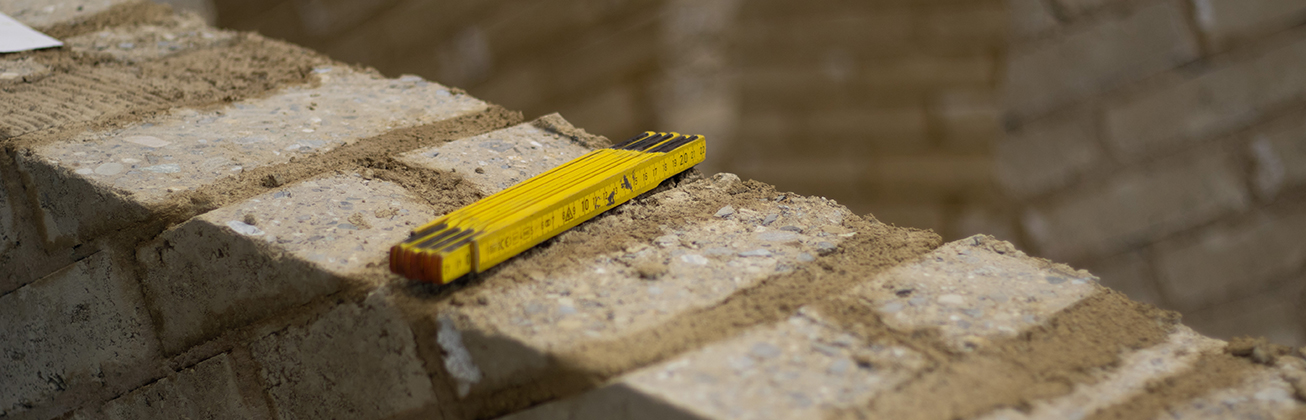Metermass auf einer Lehmmauer