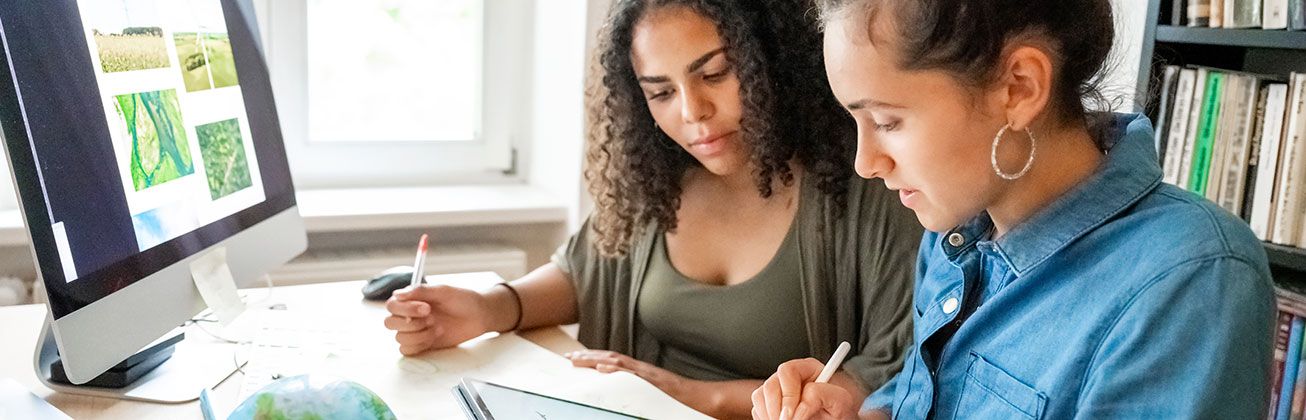 Zwei junge Frauen arbeiten zusammen am Computer