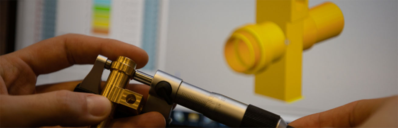 Mechanische Systeme Symbolbild: Jemand hält eine Messvorrichtung in der Hand und im Hintergrund ist das CAD zu sehen.