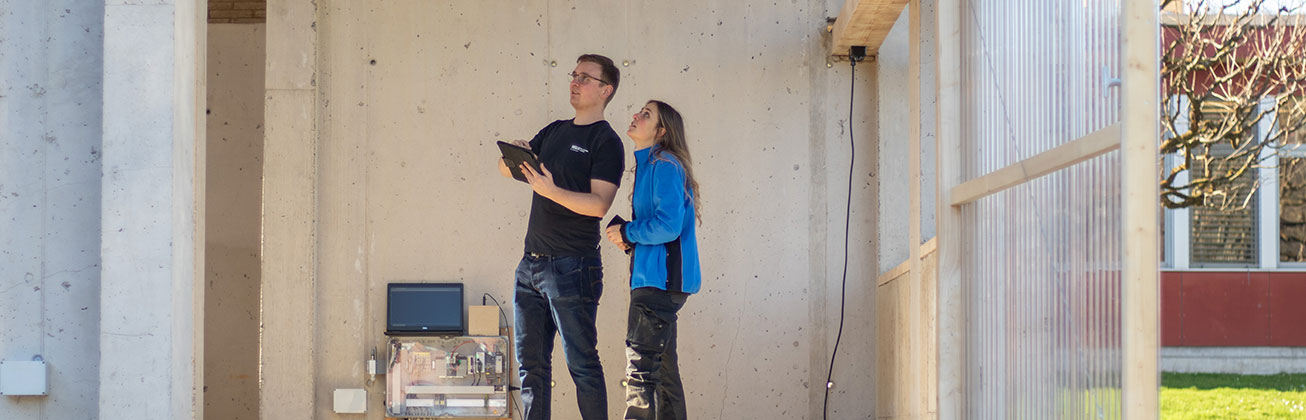 Zwei junge Forschende begutachten den Lehm-Pavilion Manal