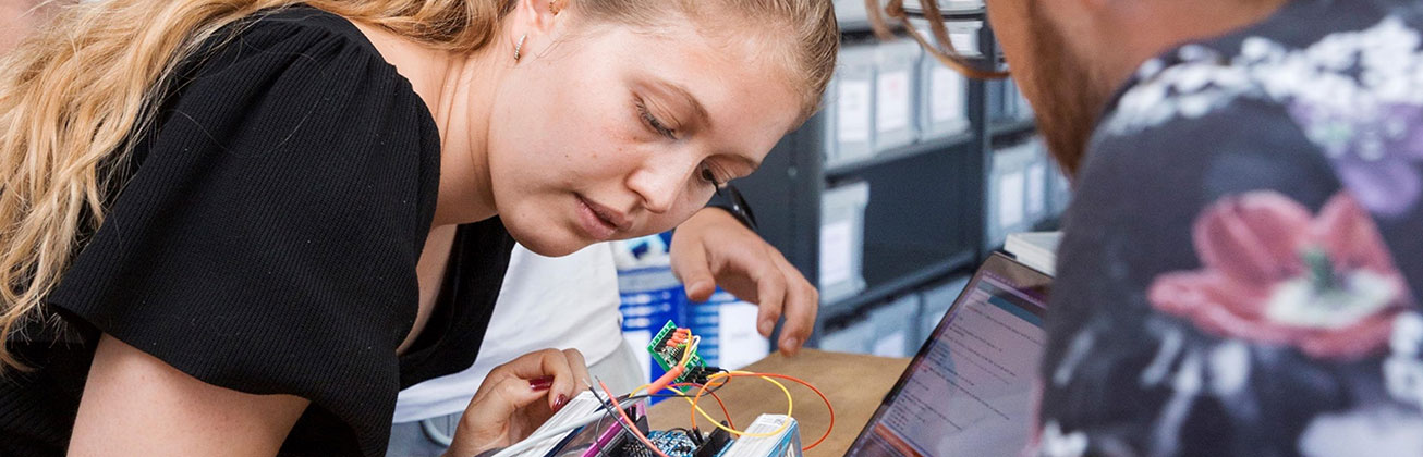 Frau und Mann, die zusammen an etwas Technischem arbeiten