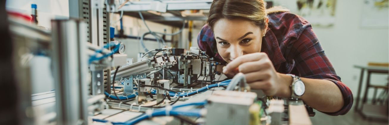 Studentin arbeitet konzentriert an einer komplexen Maschinenbau-Versuchsanlage im Labor