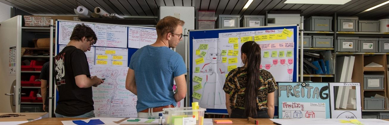 Studierende entwickeln gemeinsam Ideen an Whiteboards mit Notizen und Diagrammen