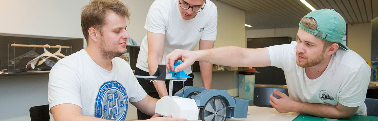 Drei Studenten arbeiten an einem Roboter