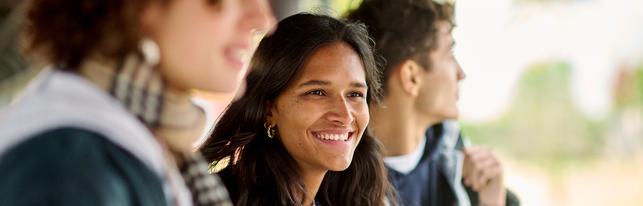 Drei Studierende aus der Nähe wobei der Fokus auf der mittleren Studentin liegt