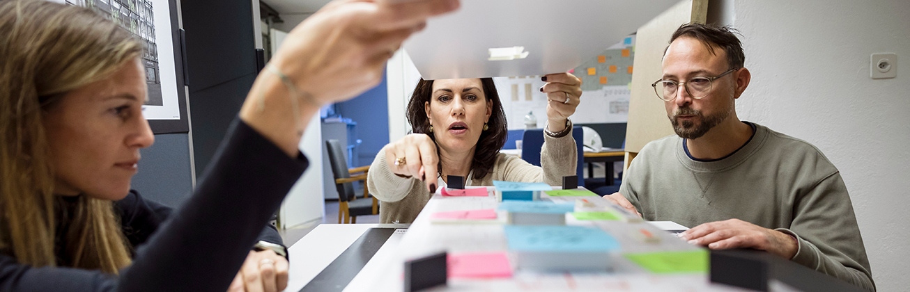 drei personen im buero schauen auf ein modell