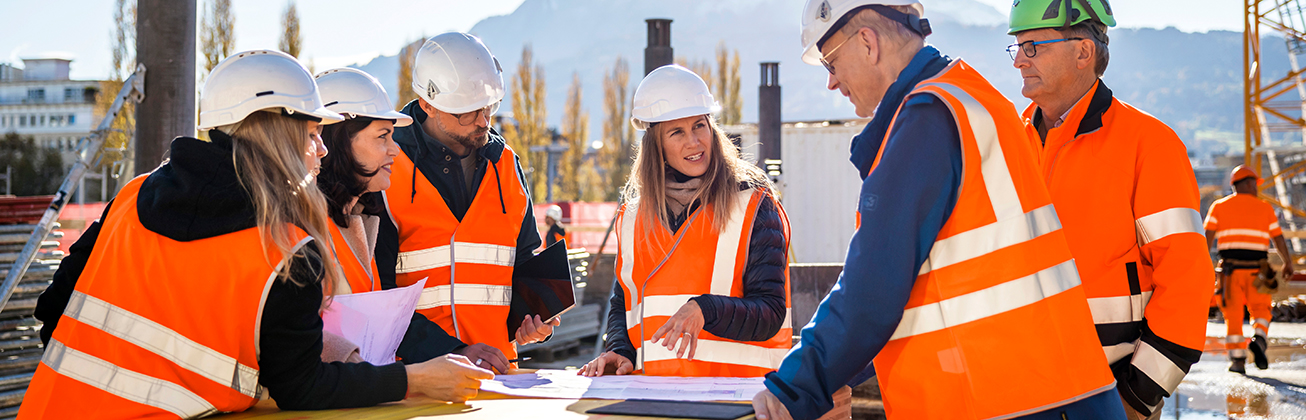 fuenf personen auf der baustelle schauen auf einen plan
