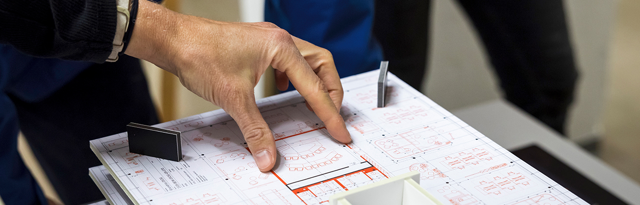 maennerhand zeigt auf baumodell