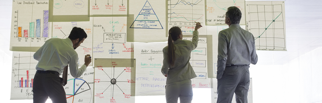 Zwei Männer und eine Frau zeichnen etwas an ein Board