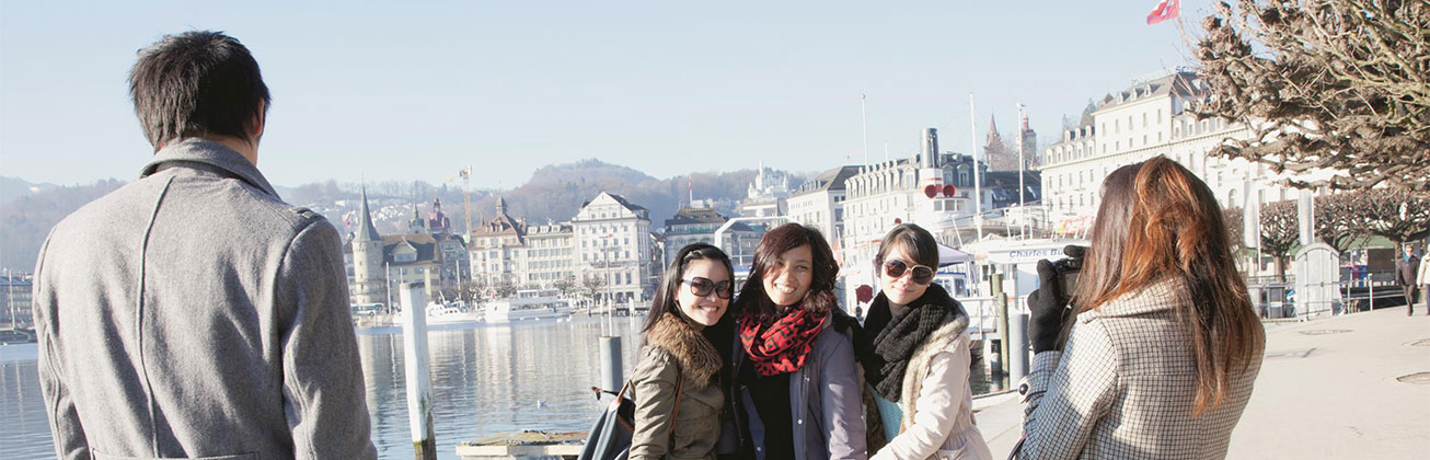 Asiatische Touristen am Foto machen, See und Gebäude im Hintergrund