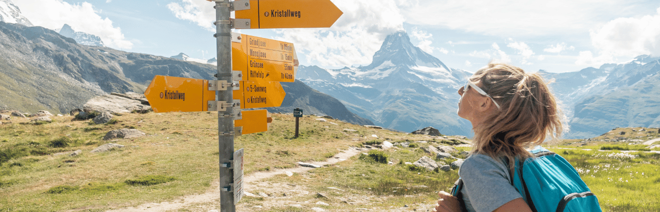 frau vor Wegweiser in den Bergen