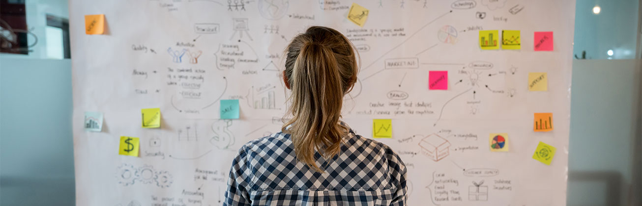 Frau steht vor Wand mit Zettel