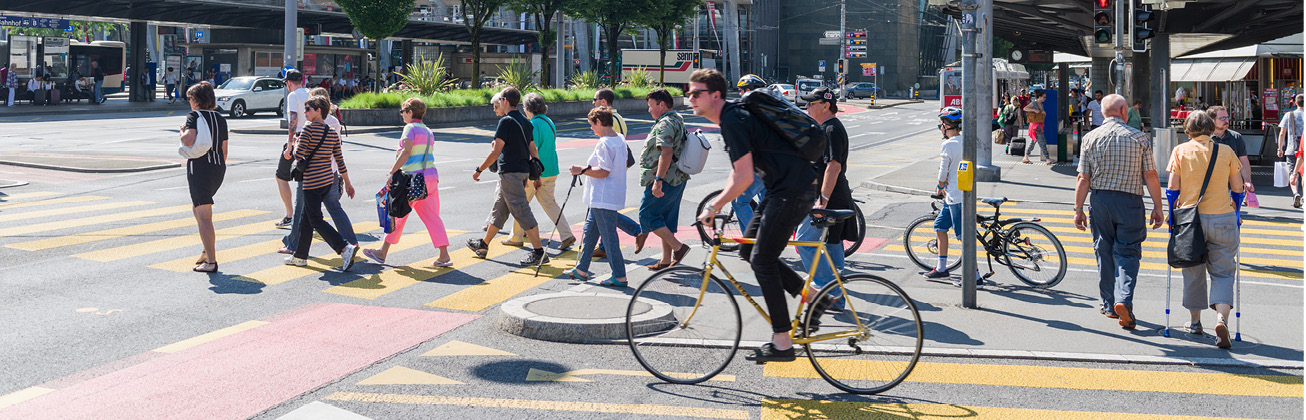 Personen am Bahnhof Luzern welche die Strasse überqueren eine Person auf dem Fahrrad