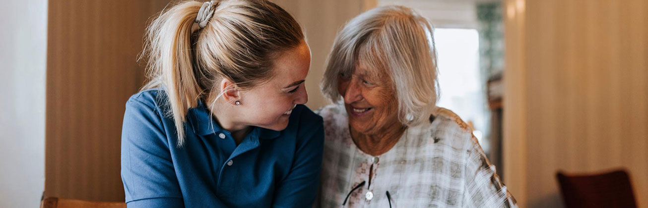 Jüngere Frau mit älterer Dame die sich zulächeln