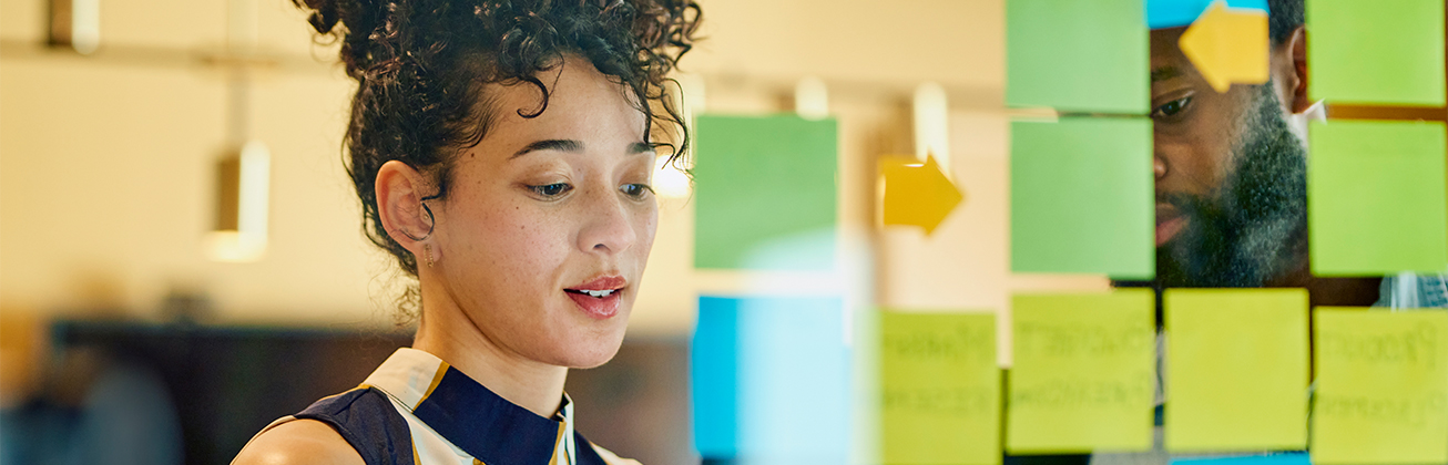 Studierende diskutieren an einer Glaswand mit farbigen Post-its