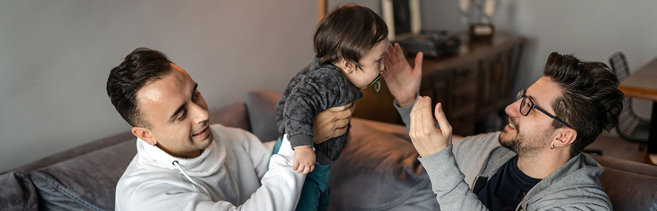 Zwei Männer spielen mit einem Kleinkind