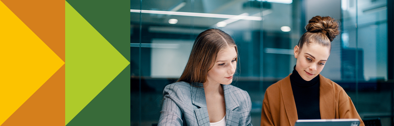 Zwei junge Personen im Business-Outfit analysieren gemeinsam Inhalte rund um das Brand Management auf einem Laptop in einem modernen Büro.