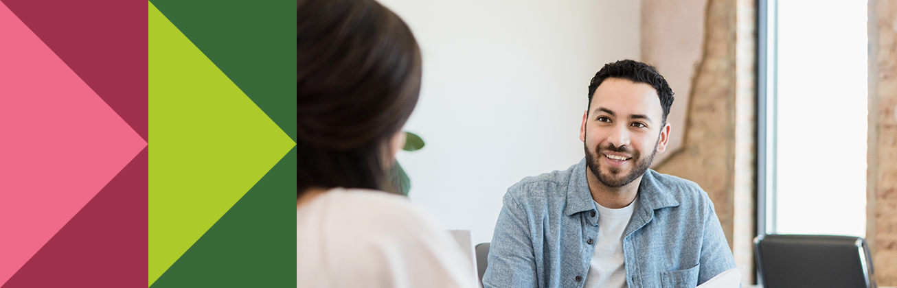 Eine Person im Gespräch mit einer anderen Person und hält Unterlagen zu strategischer Content-Planung in der Hand. Sinnbildlich für zielgerichtete Kommunikation und partnerschaftliche Beratung im Marketing.