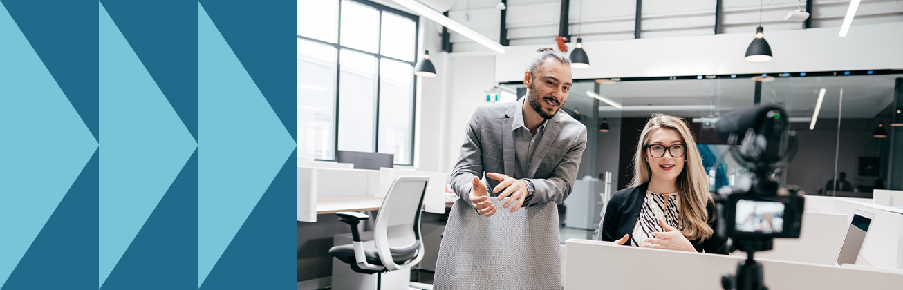 Eine Frau spricht vor einer Kamera, während ein Mann daneben etwas erklärt – Symbolbild für professionelle Content-Erstellung, zielgerichtete Verbreitung und mediengerechte Kommunikation.