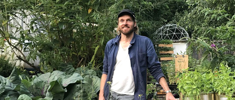 Marco Clausen stands in a urban garden
