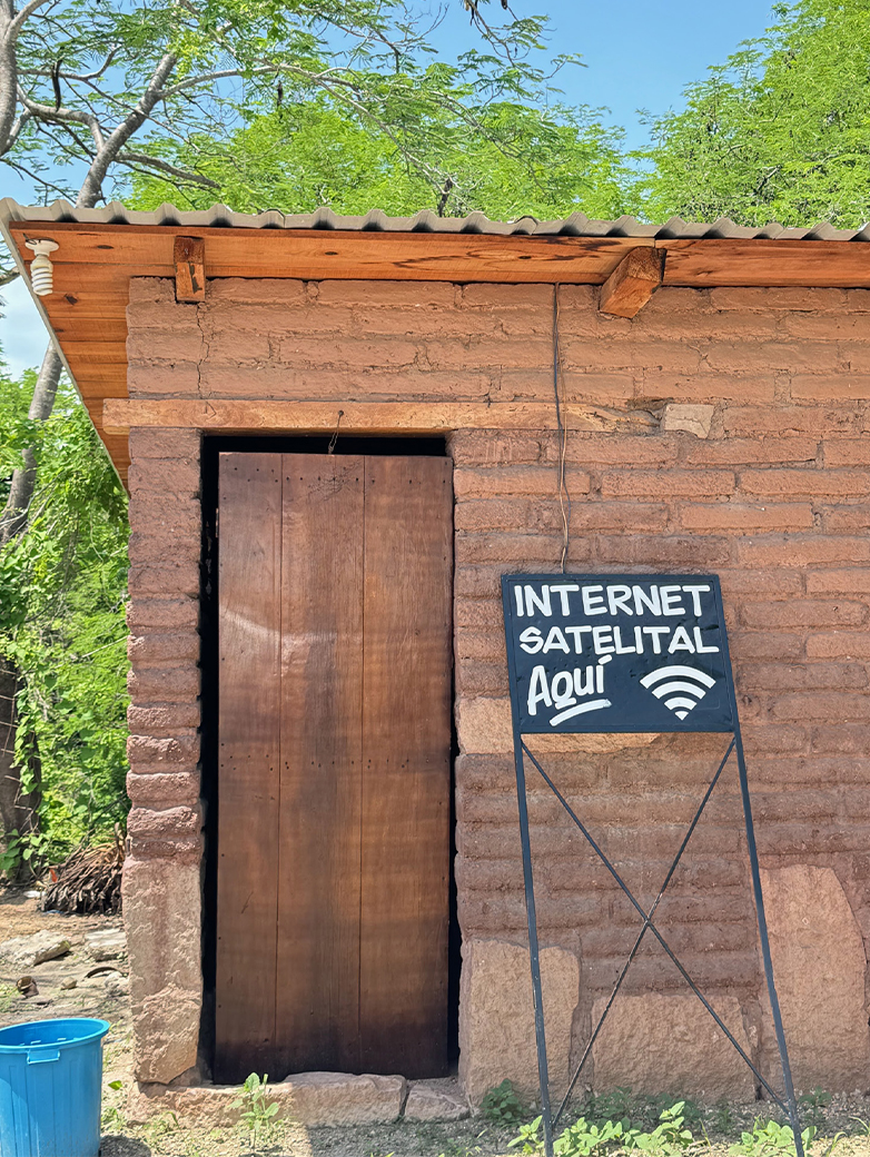 EIn leerstehendes Ziegelhaus mit Holztüre und dem Schild Internet Satelital Aqui.