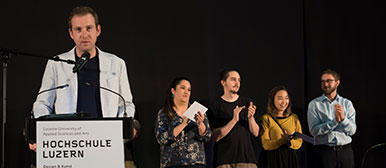 Thomas Etienne, Laudator und Stiftungsrat der zeugindesign-Stiftung mit Preisträgern und Preisträgerinnen im Hintergrund 