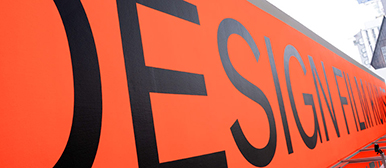 Aussenbeschriftung Gebäude mit den Wörtern Design Film Kunst auf leuchtorangem Hintergrund