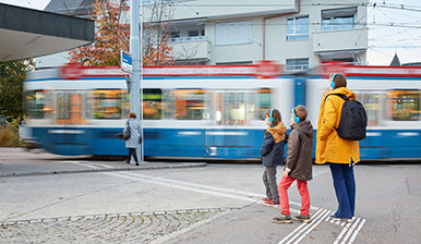 Eine Familie trägt blaue Kopfhörer und bewegt sich durch die Stadt Zürich