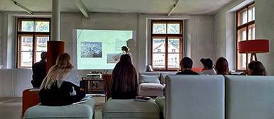 Das Bild zeigt Personen in einem Raum die einer Veranstaltung folgen.