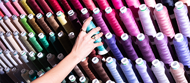 Textildesign an der HSLU Design Kunst – Hand greift nach farbigen Garnrollen in der Werkstatt für Gestaltung.