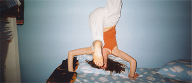 Bild einer Frau, die einen Handstand auf einem Bett macht. Das Bild verlinkt auf die Personen-Seite des Bachelor Creative Transformation. 