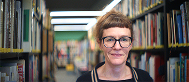 Kat Woodtli, Dozentin im Bachelor Animation an der HSLU Luzern, in der Fachbibliothek zwischen Bücherregalen.