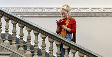 Studierende steht auf der Treppe und schreibt ins Notizbuch