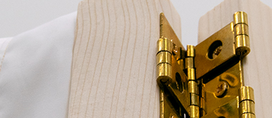     Detailaufnahme eines goldfarbenen Scharniers, das zwei helle Holzelemente verbindet und handwerkliche Konstruktion sichtbar macht.