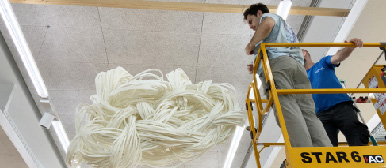 Mit einer gelben Hebebühne wird ein künstlerisches Objekt aufgehängt