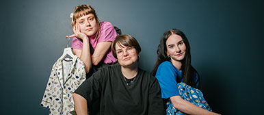 Drei Studierende posieren in ihren Designs