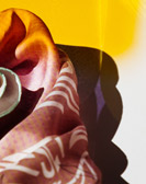 Ein brauner Stoff mit weissem Muster, der verkrumpelt vor einem weiss-gelben Hintergrund ist