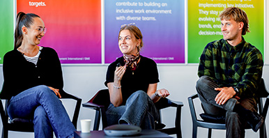 Drei Alumni von DMI sitzen zusammen und präsentieren