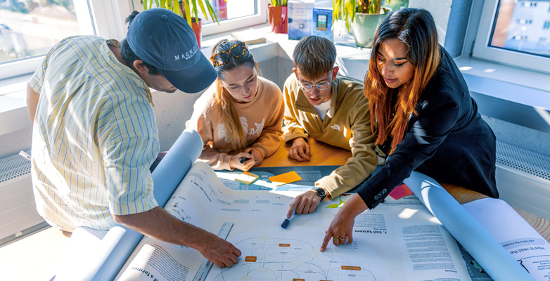Eine Gruppe von Studierenden bespricht eine Infografik